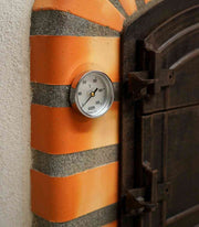 Close-up van een ingebouwde analoge thermometer in de oranje-rode terracotta boog van een steenoven